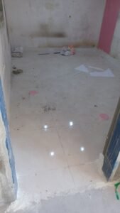 عامل يقوم بإصلاح بلاط متضرر ومعالجة الهبوط في الأرضيات باستخدام مواد ترميم قوية